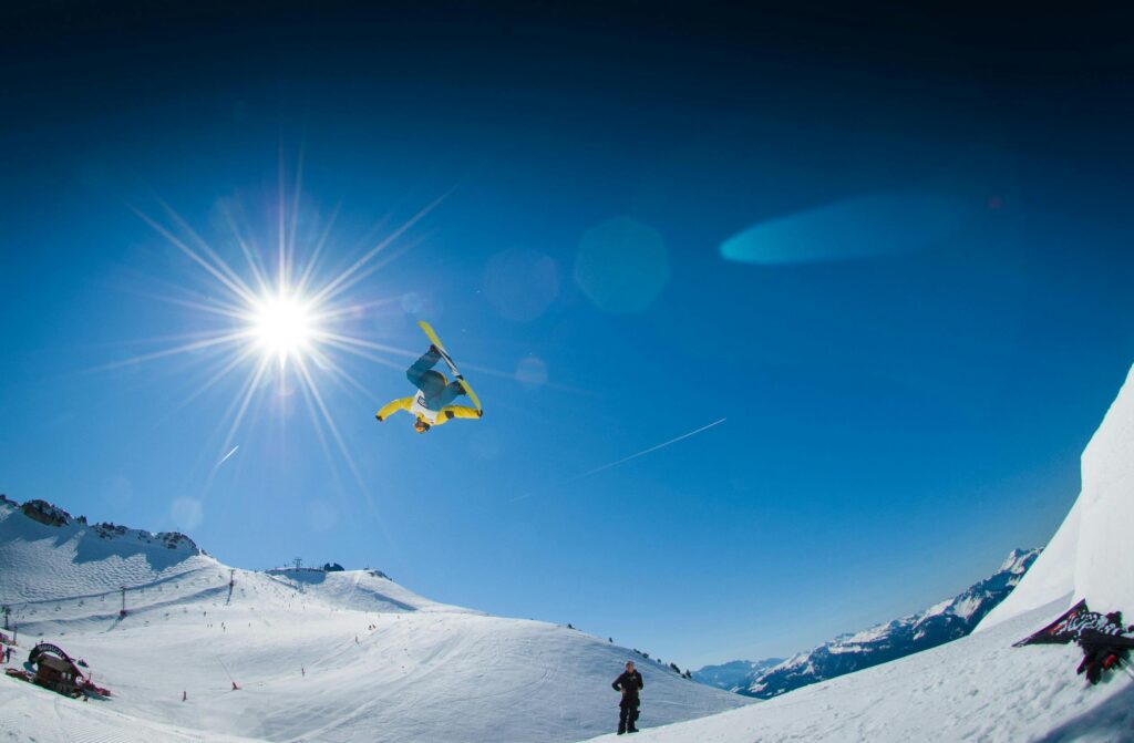 Snowboarder executing a freestyle trick in the sunny winter Alps.